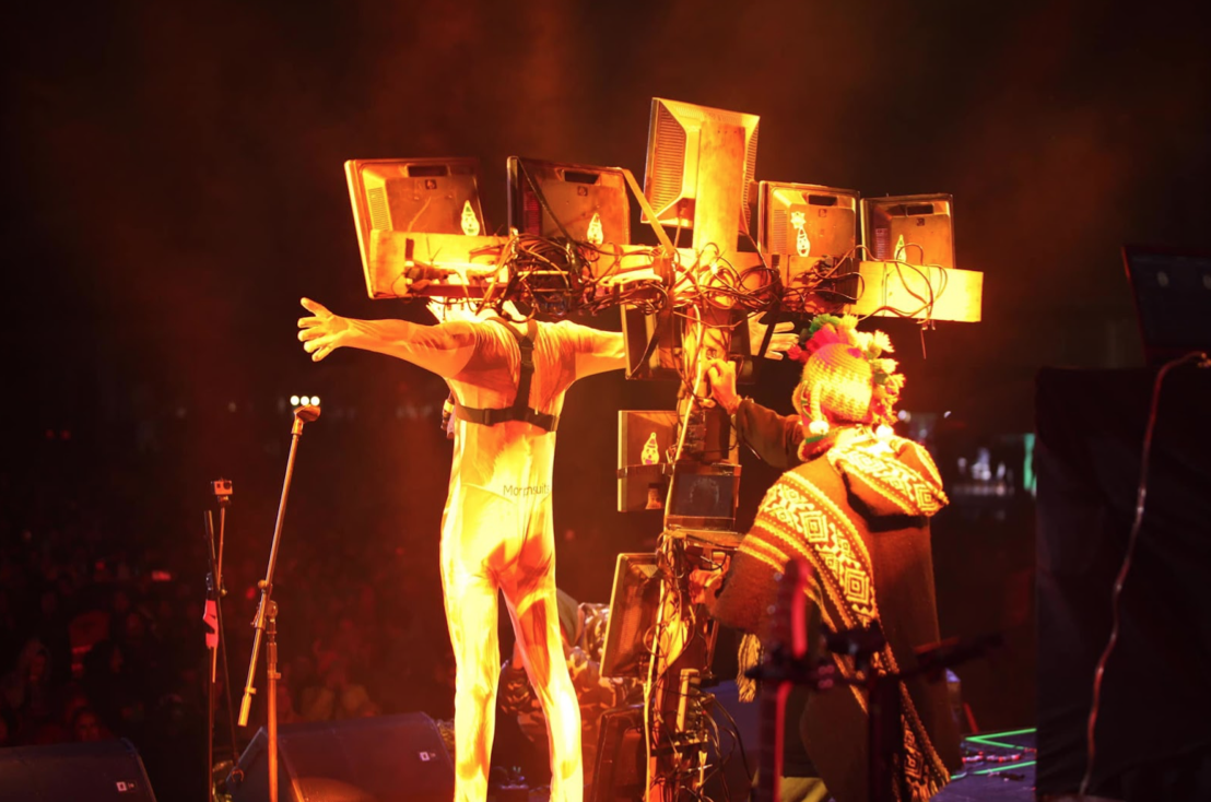 Performance en escenario de Quitofest, diciembre de 2024. Una cruz armada de televisores. Y la exhibición del exoesqueleto del “Homo ecuatoriano” promedio.
