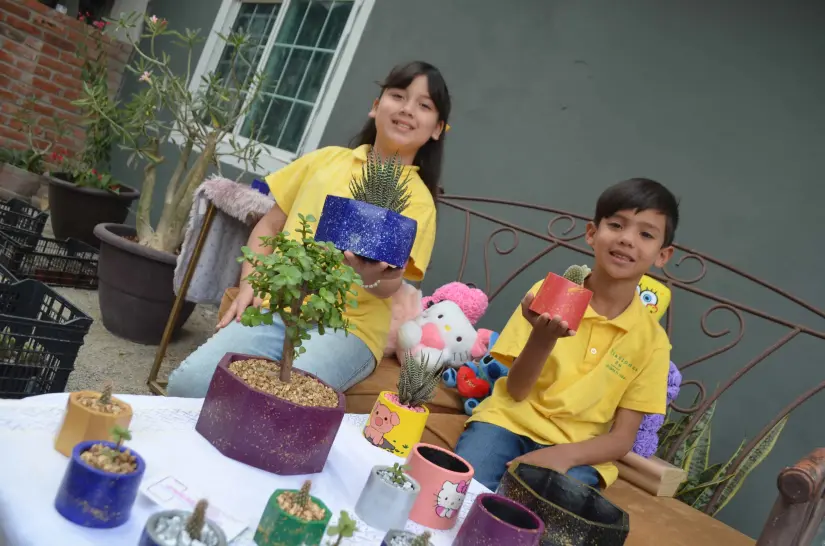 Camila a lado de su hermano y plantas
