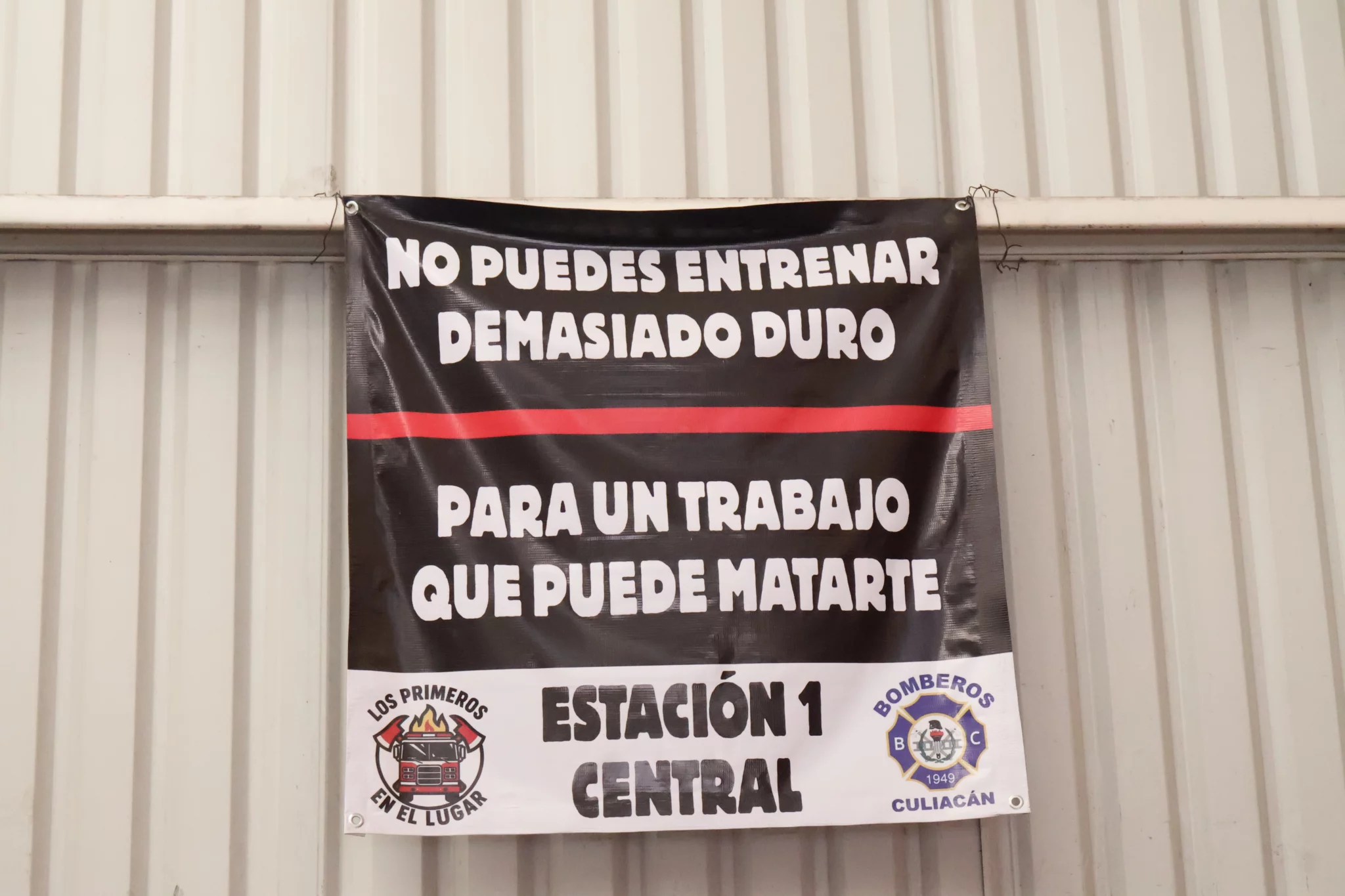 Letrero en la Estación Central de Bomberos de Culiacán advierte sobre el riesgo del oficio y la importancia del entrenamiento para salvar vidas.
